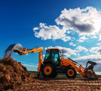 Wheel loader excavator with field background during earthmoving work, construction building